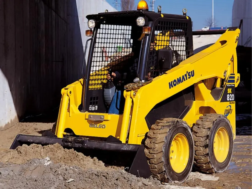 Mini cargadora Komatsu SK820 en acción realizando retiro de escombros y movimiento de áridos, utilizada por Escombros Áridos para limpieza y preparación de terrenos en obras de construcción.