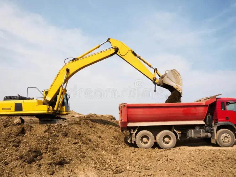 Maquinaria pesada en faena de movimiento de tierra, con una excavadora amarilla cargando un camión tolva rojo de Escombros Áridos en Santiago.