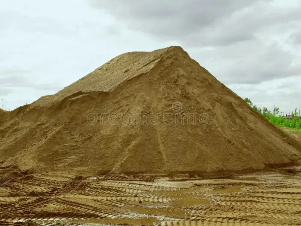 Gran montón de arena gruesa en el patio de Escombros Áridos, con huellas de camión en el suelo, listo para despacho en la Región Metropolitana.