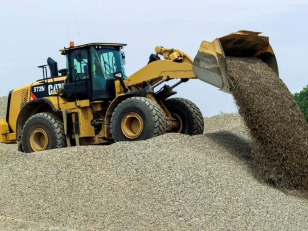 Cargador frontal amarillo de Escombros Áridos moviendo una gran cantidad de grava de construcción, demostrando nuestra capacidad para gestionar grandes volúmenes.