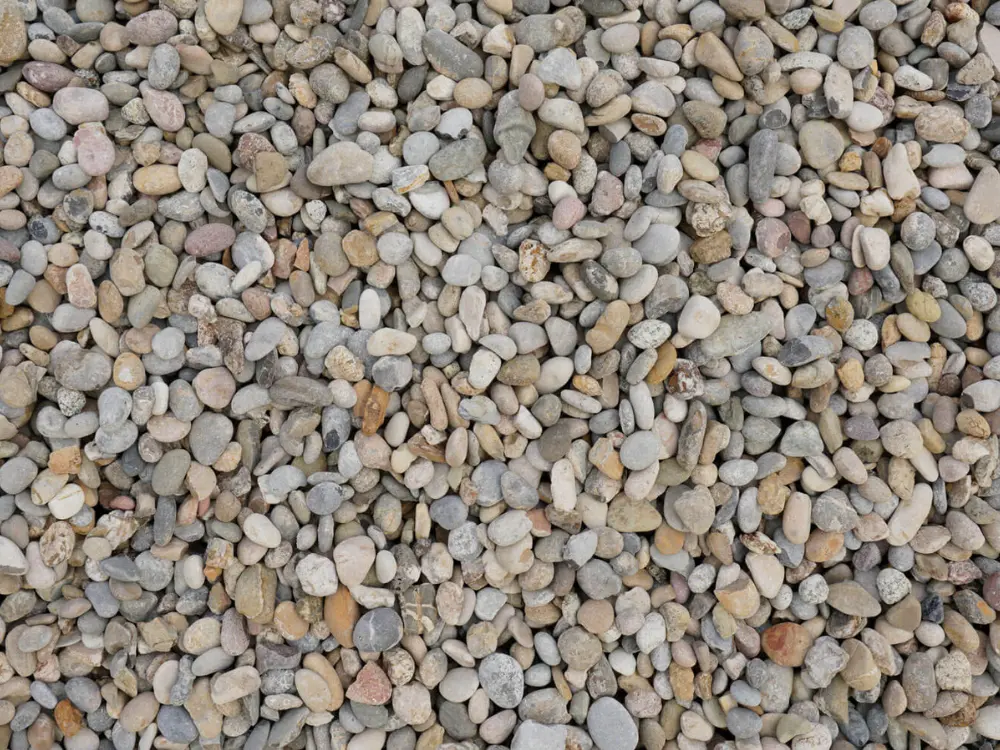 Textura de canto rodado ofrecido por Escombros Áridos. La imagen muestra un primer plano de piedras de río redondeadas y lisas, de colores variados como gris y beige, ideales para la decoración de jardines en Santiago.