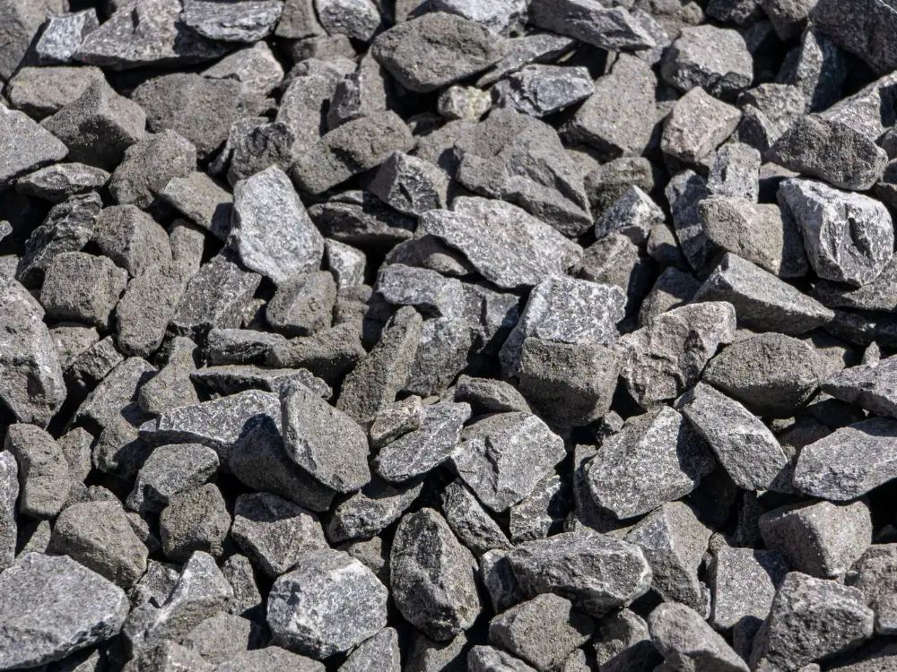 Imagen en primer plano de la textura de gravilla 3/4 de color gris oscuro, destacando sus bordes angulares. Es un árido triturado ideal para mezclas de hormigón y bases, suministrado por Escombros Áridos.