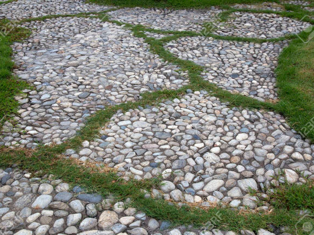 Sendero de jardín con un diseño orgánico de canto rodado y césped en las juntas, una idea de paisajismo con áridos decorativos de Escombros Áridos.