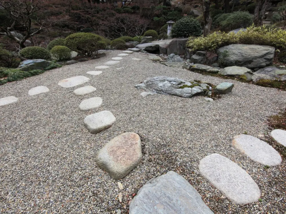 Jardín zen o camino paisajístico con gravilla decorativa y grandes piedras de paso. Este árido es perfecto para senderos y diseño de jardines, disponible a la venta en Escombros Áridos.