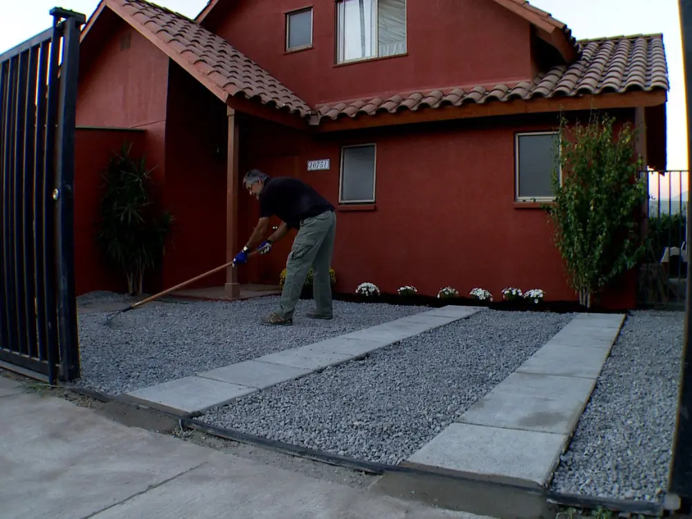 Estacionamiento comercial con gravilla para estacionamiento oscura y líneas de demarcación amarillas. Suministro de áridos de alto tráfico por Escombros Áridos.