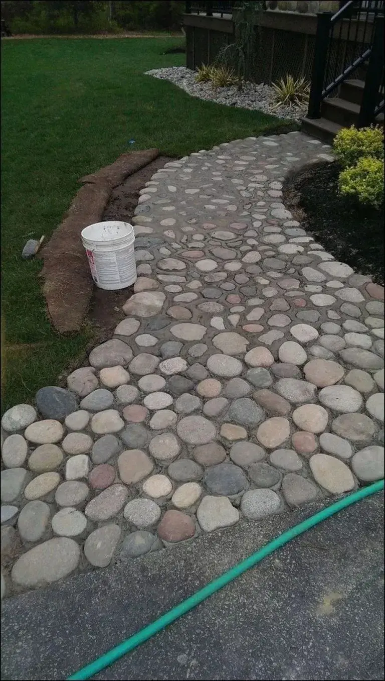Proceso de construcción de un sendero curvo de jardín con piedras de canto rodado, un diseño rústico y duradero creado con áridos de Escombros Áridos.