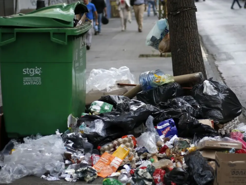 Retiro de basura Puente Alto: bolsas y residuos acumulados junto a contenedor verde en la vereda, servicio de limpieza y retiro de basura voluminosa.