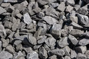 Imagen en primer plano de la textura de gravilla 3/4 de color gris oscuro, destacando sus bordes angulares. Es un árido triturado ideal para mezclas de hormigón y bases, suministrado por Escombros Áridos.