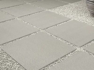 Diseño moderno de piso exterior con baldosas cuadradas y juntas rellenas con gravilla fina, utilizada para drenaje eficiente y estética. Gravilla de alta calidad disponible en Escombros Áridos.