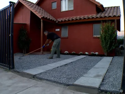 Estacionamiento comercial con gravilla para estacionamiento oscura y líneas de demarcación amarillas. Suministro de áridos de alto tráfico por Escombros Áridos.
